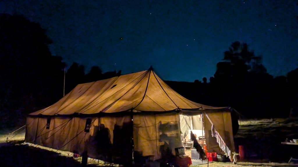 A large canvas marquee glowing gold at night under a starry sky